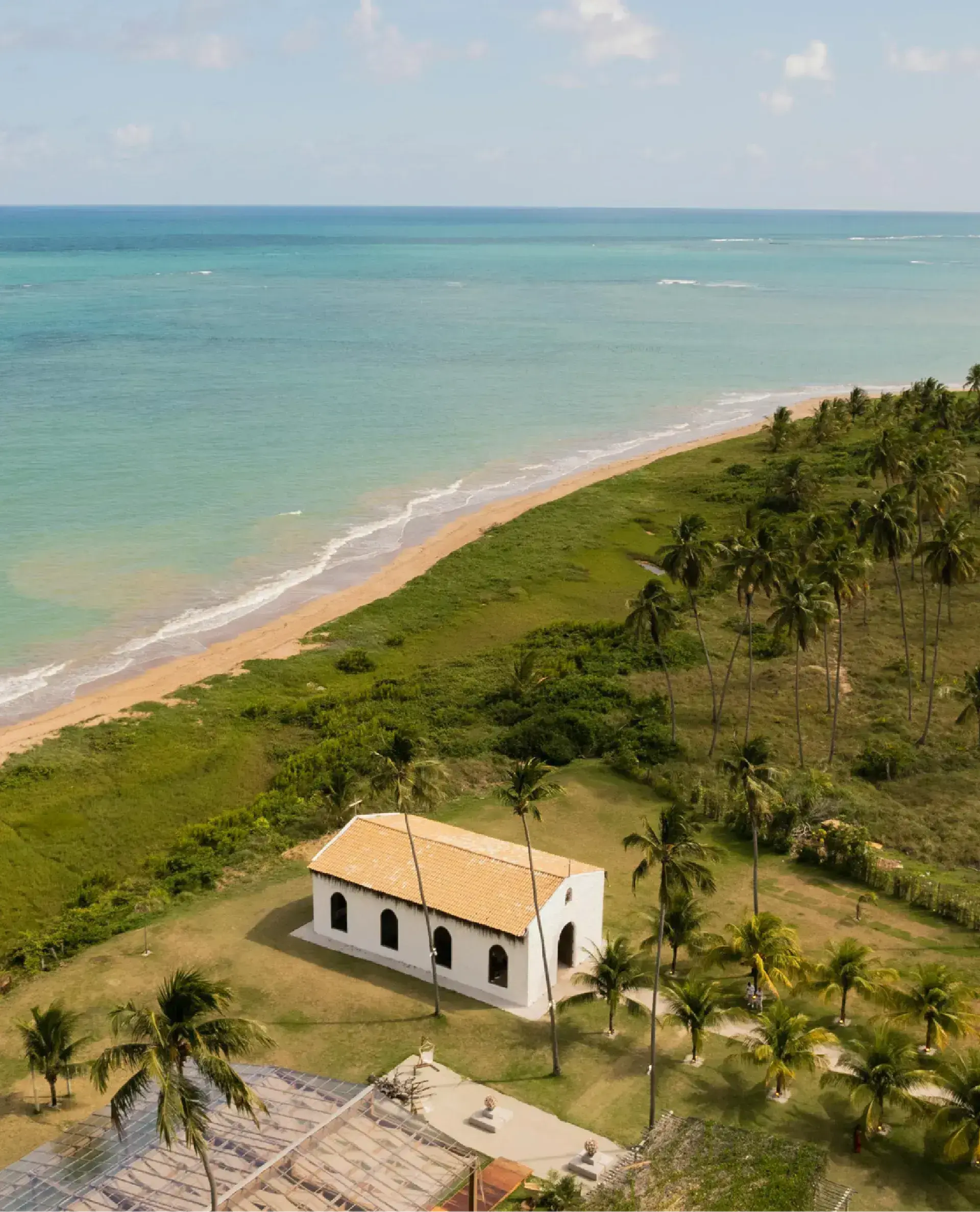 Foto de uma igreja próxima à praia com várias palmeiras ao redor